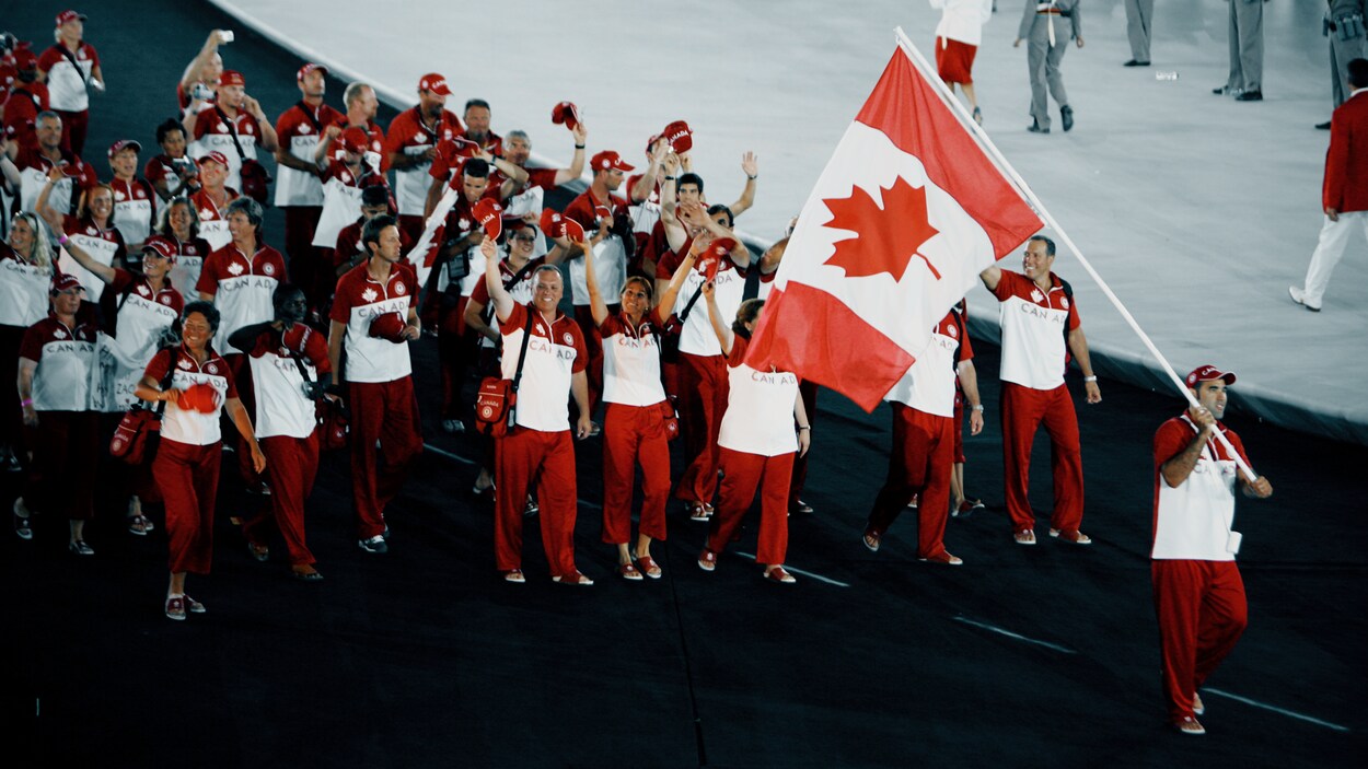 Nicolas Gill agite le drapeau du Canada pendant que le reste de la délégation canadienne le suit. Nicolas Gill agite le drapeau du Canada pendant que le reste de la délégation canadienne le suit.