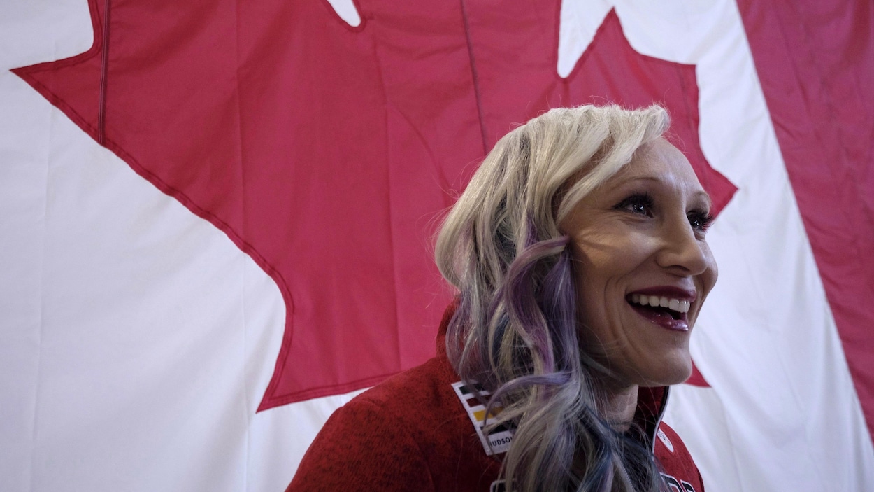 Une athlète sourit devant un drapeau canadien