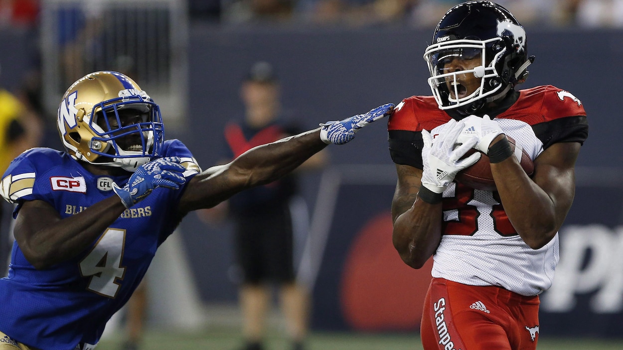Le receveur des Stampeders, Kamar Jorden, se défait d'un plaqué de Roc Carmichael, des Blue Bombers, pour inscrire un touché. Le receveur des Stampeders, Kamar Jorden, se défait d'un plaqué de Roc Carmichael, des Blue Bombers, pour inscrire un touché.