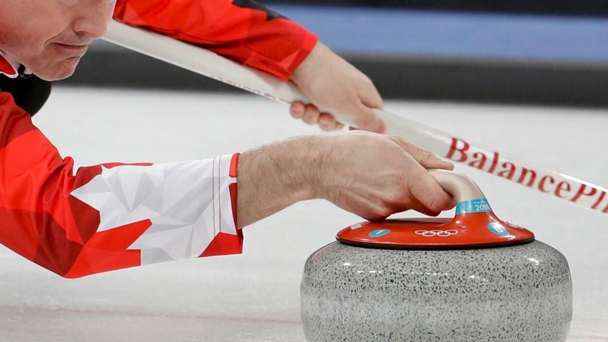 Kevin Koe lance la pierre lors d'un match de curling de l'équipe canadienne.