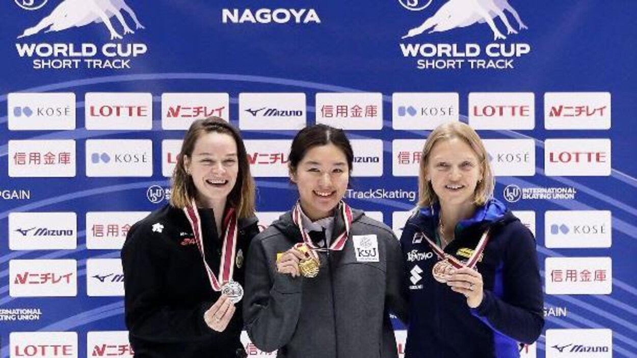 Elle montre sa médaille aux côtés de ses rivales.