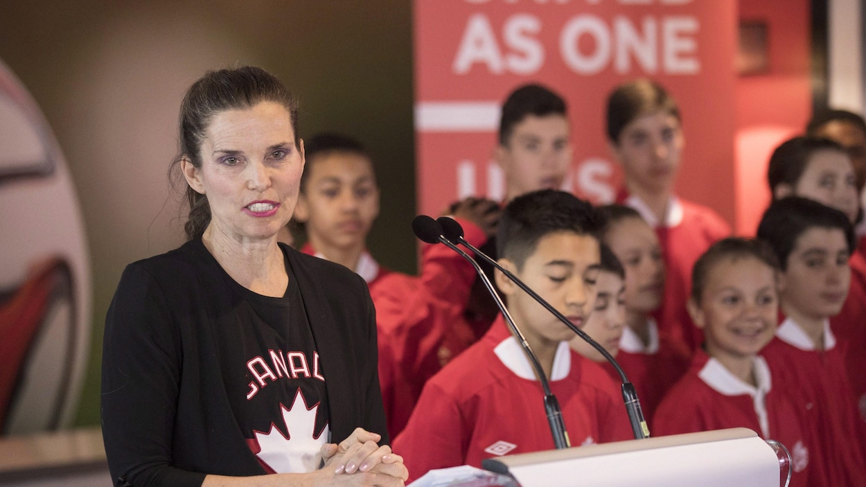 La ministre Kirsty Duncan fait un discours devant un micro. Un groupe de jeunes se tient derrière elle.