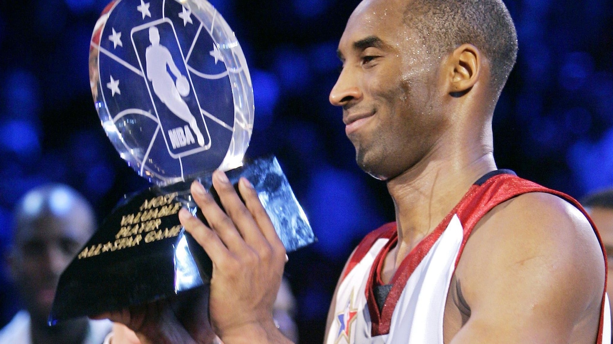 Il tient le trophée dans ses mains.