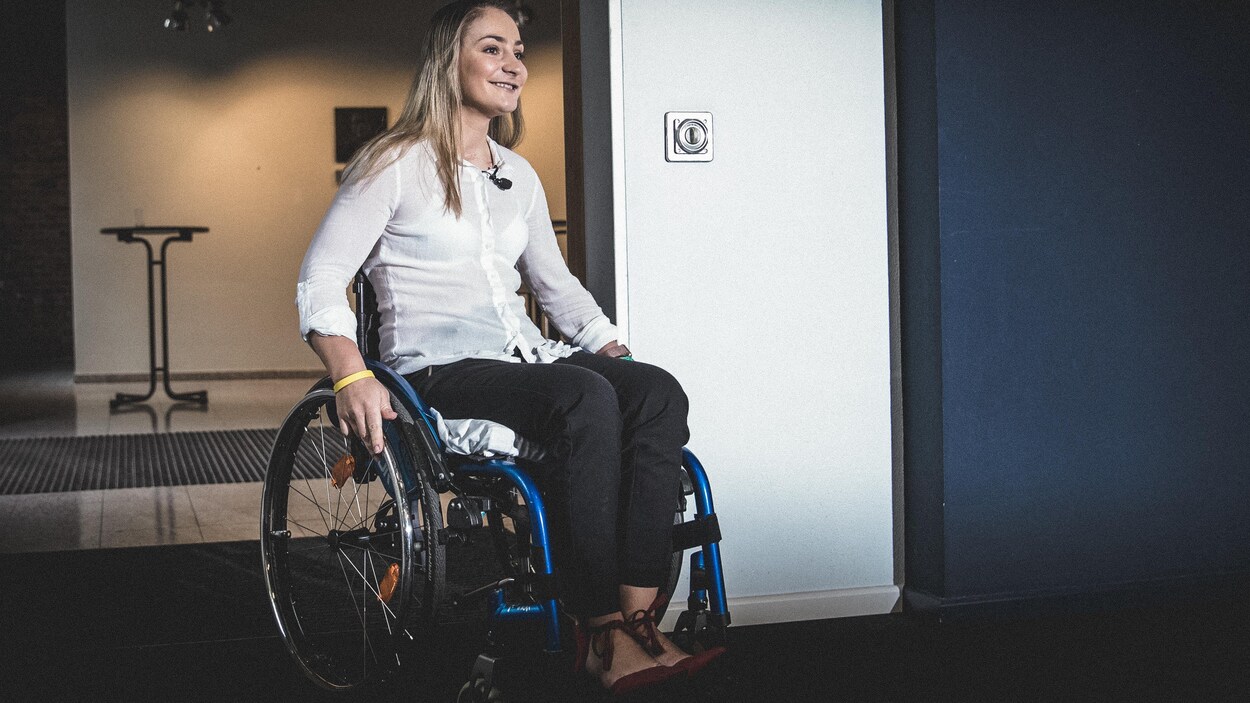 Kristina Vogel, souriante, est assise dans un fauteuil roulant. Kristina Vogel, souriante, est assise dans un fauteuil roulant.