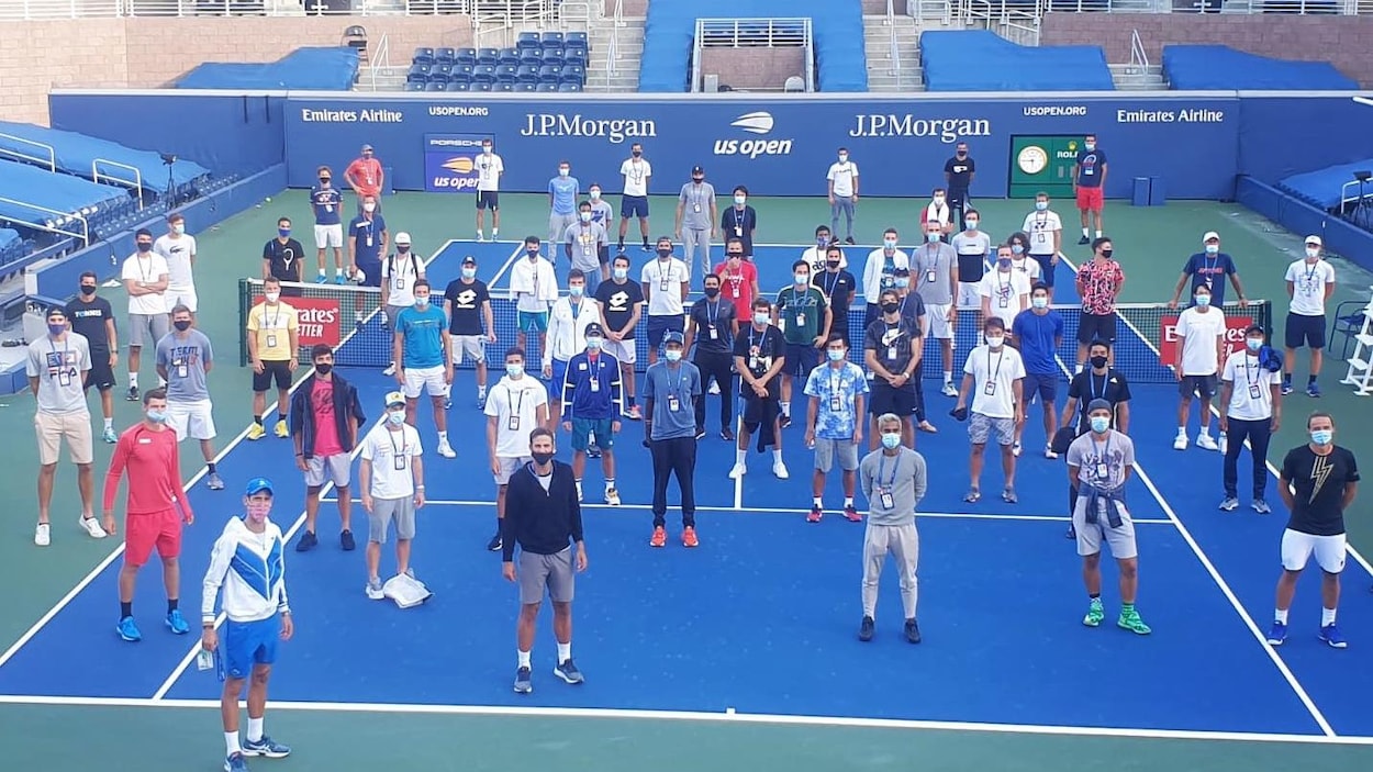 Une quarantaine de joueurs masqués sur un court de tennis.