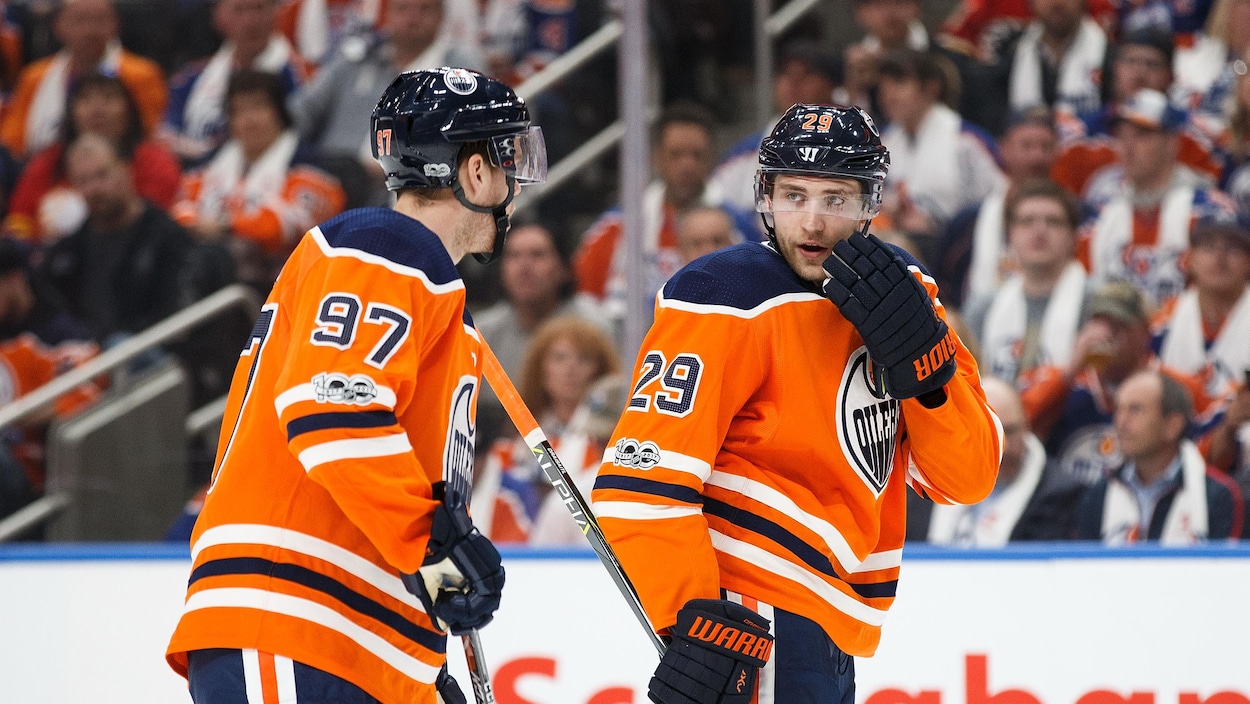Connor McDavid et Leon Draisaitl des Oilers discutent stratégie lors d'un match face aux Flames Connor McDavid et Leon Draisaitl des Oilers discutent stratégie lors d'un match face aux Flames