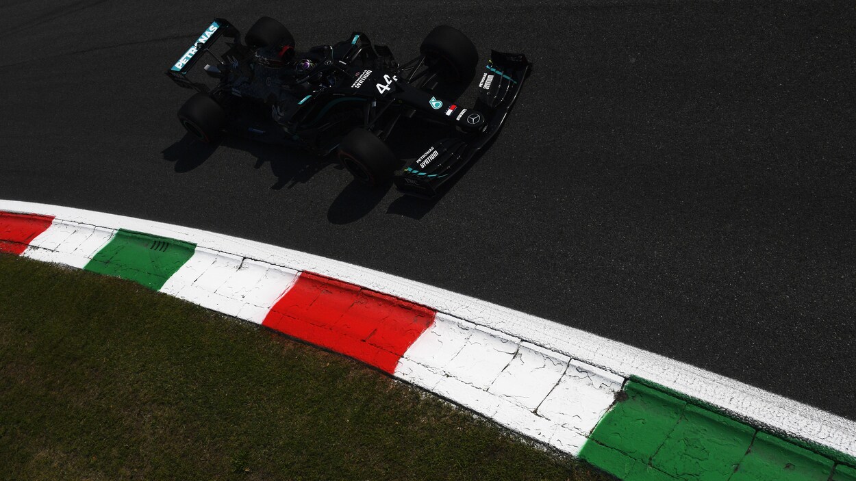 Il roule sur un circuit dans sa Mercedes-Benz noire.