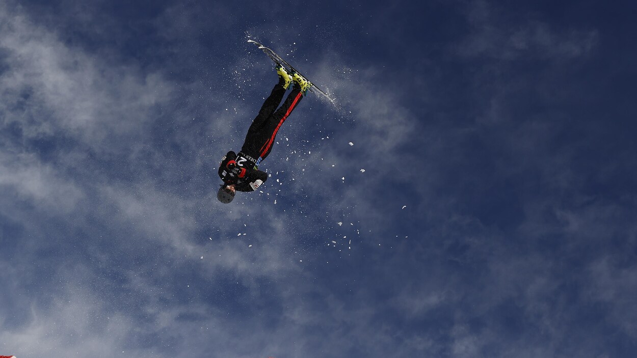 Un sauteur acrobatique est dans les airs à la sortie du tremplin. 