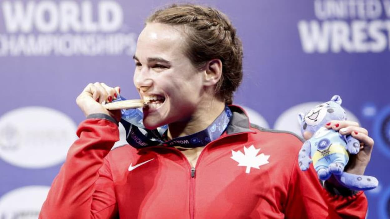 Une athlète mord à pleines dents dans sa médaille d'or.