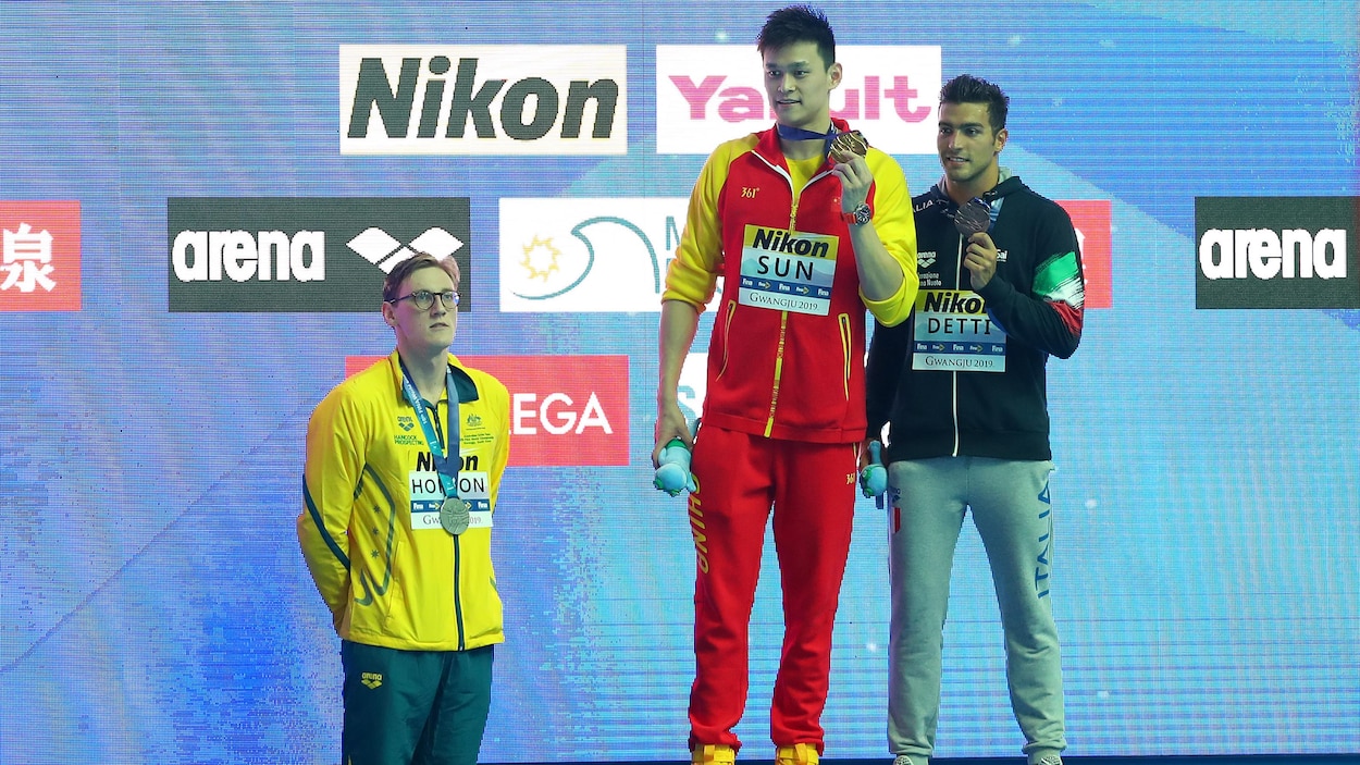 Horton demeure au pied du podium alors que Sun Yang, et l'Italien Gabriele Detti, en bronze, posent lors de la cérémonie de remise des médailles.