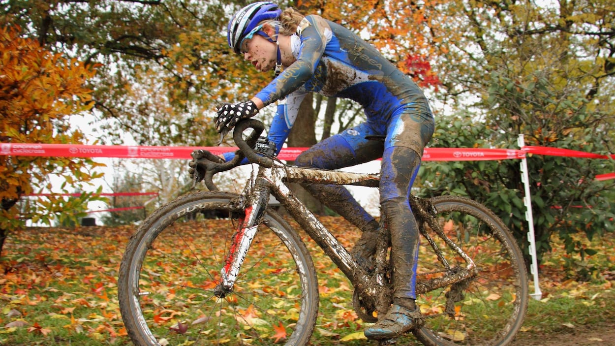 Elle pédale pendant une course sur une route boueuse.