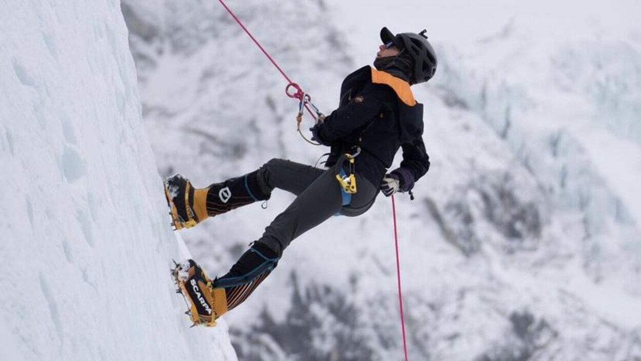La femme grimpe l'Everest attachée à une corde.