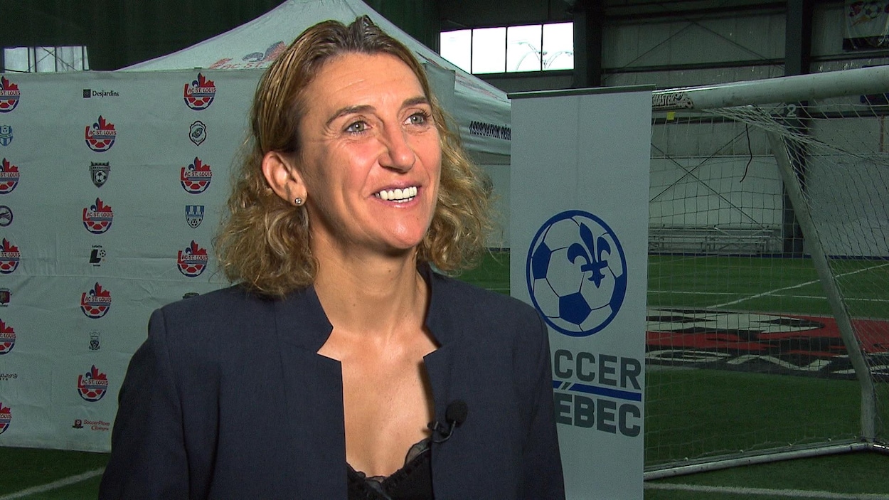 Elle sourit sur un terrain d'entraînement intérieur.