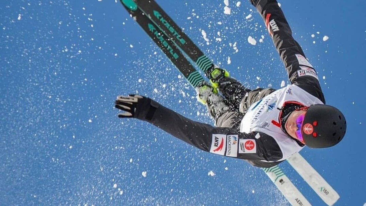 Une skieuse effectue un saut, la tête en bas.