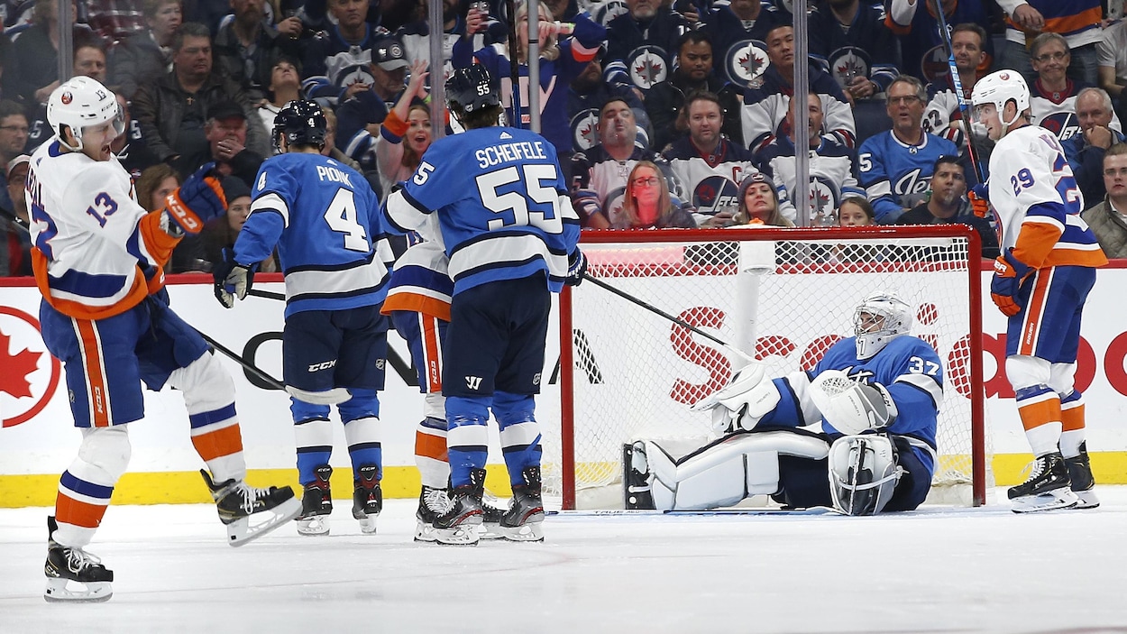 Le poing dans les airs, il célèbre son but devant Connor Hellebuyck, assis sur la glace.