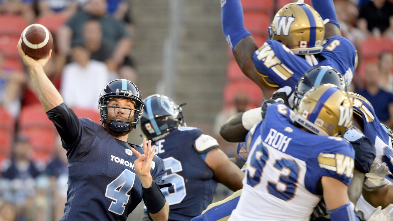 Un joueur des Blue Bombers saute dans les airs pour la bloquer.