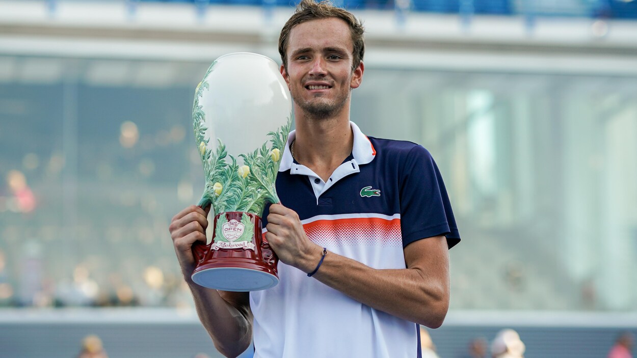 Il montre le trophée du gagnant à la foule.