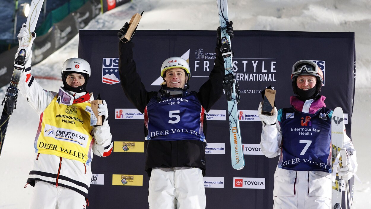 Trois bosseurs, avec leurs skis, tiennent leur trophée dans les mains.