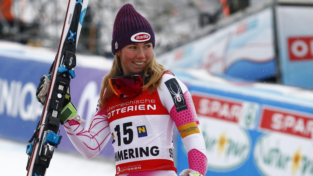 Elle tient ses skis et sourit dans l'aire d'arrivée.