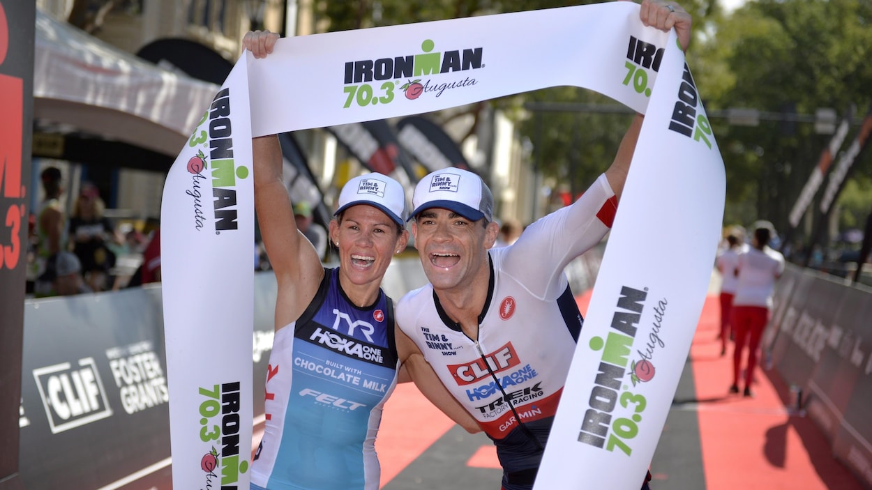 Un couple d'athlètes prend une pose pour la photo au fil d'arrivée d'un Ironman à Augusta, en Georgie, en 2016.