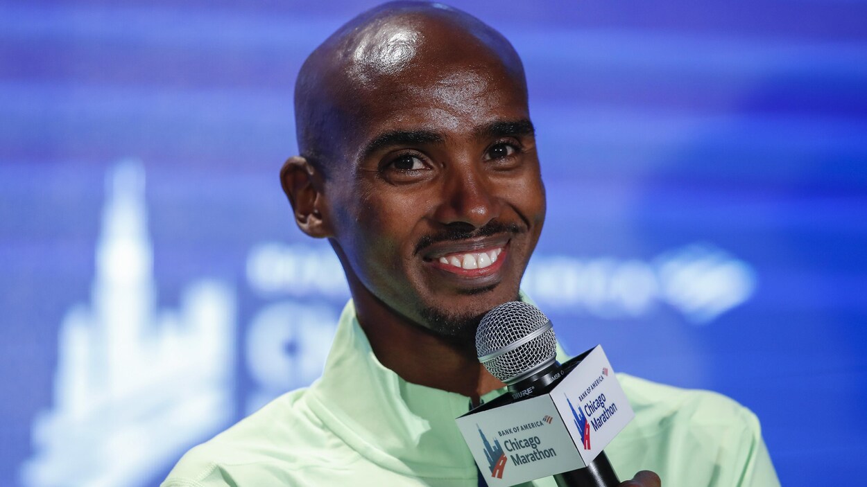 Mo Farah tient un micro dans sa main.