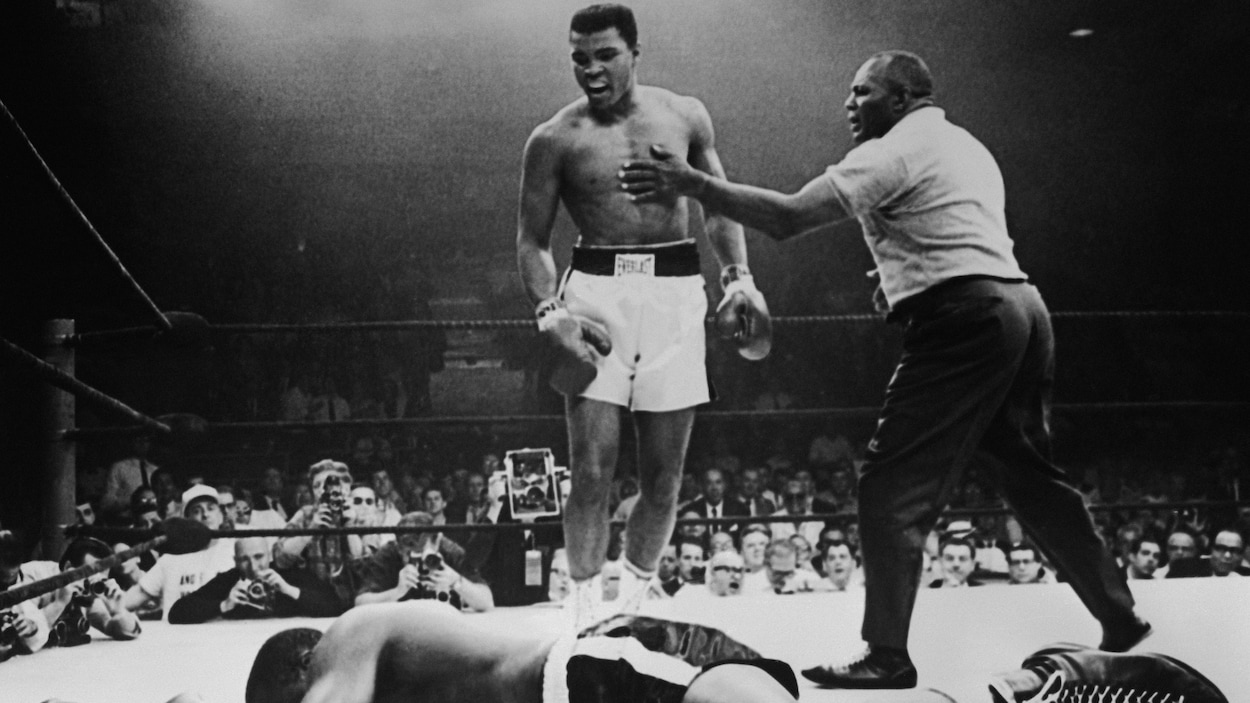 Un boxeur étendu au sol près du boxeur qui l'a fait tomber.