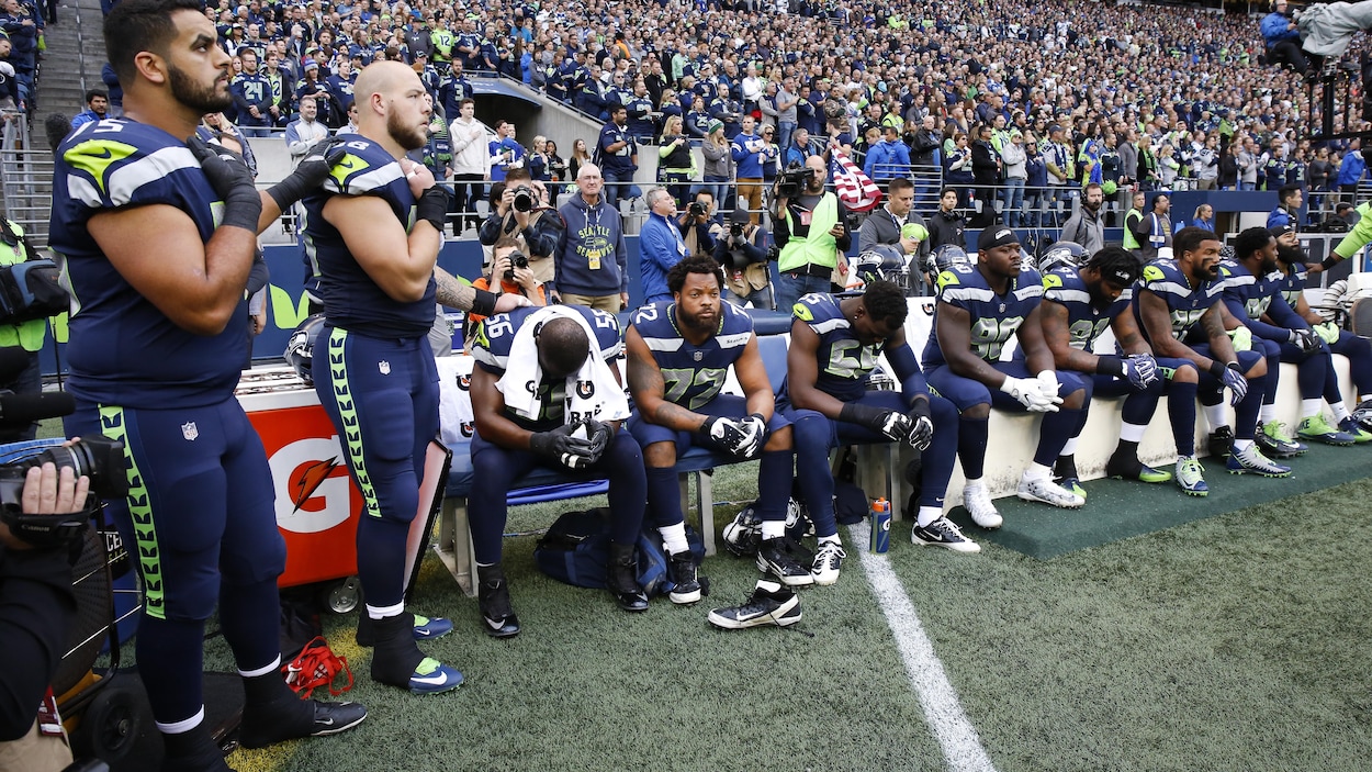 Les joueurs des Seahawks de Seattle assis lors de l'hymne national américain.