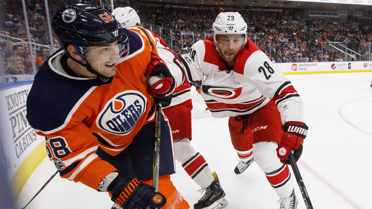Elias Lindholm pousse Anton Slepyshev dans le coin de la patinoire. Elias Lindholm pousse Anton Slepyshev dans le coin de la patinoire.