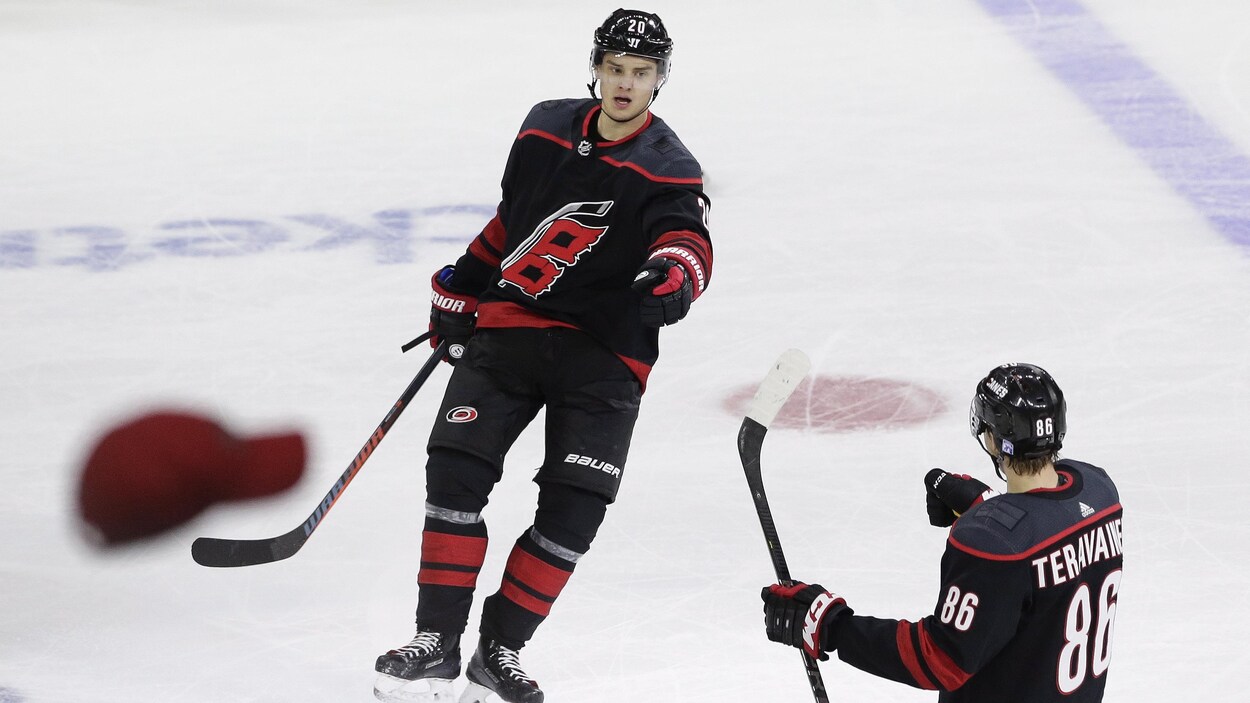 Sebastian Aho célèbre son troisième but du match avec Teuvo Teravainen, alors que la foule lance des chapeaux sur la glace.