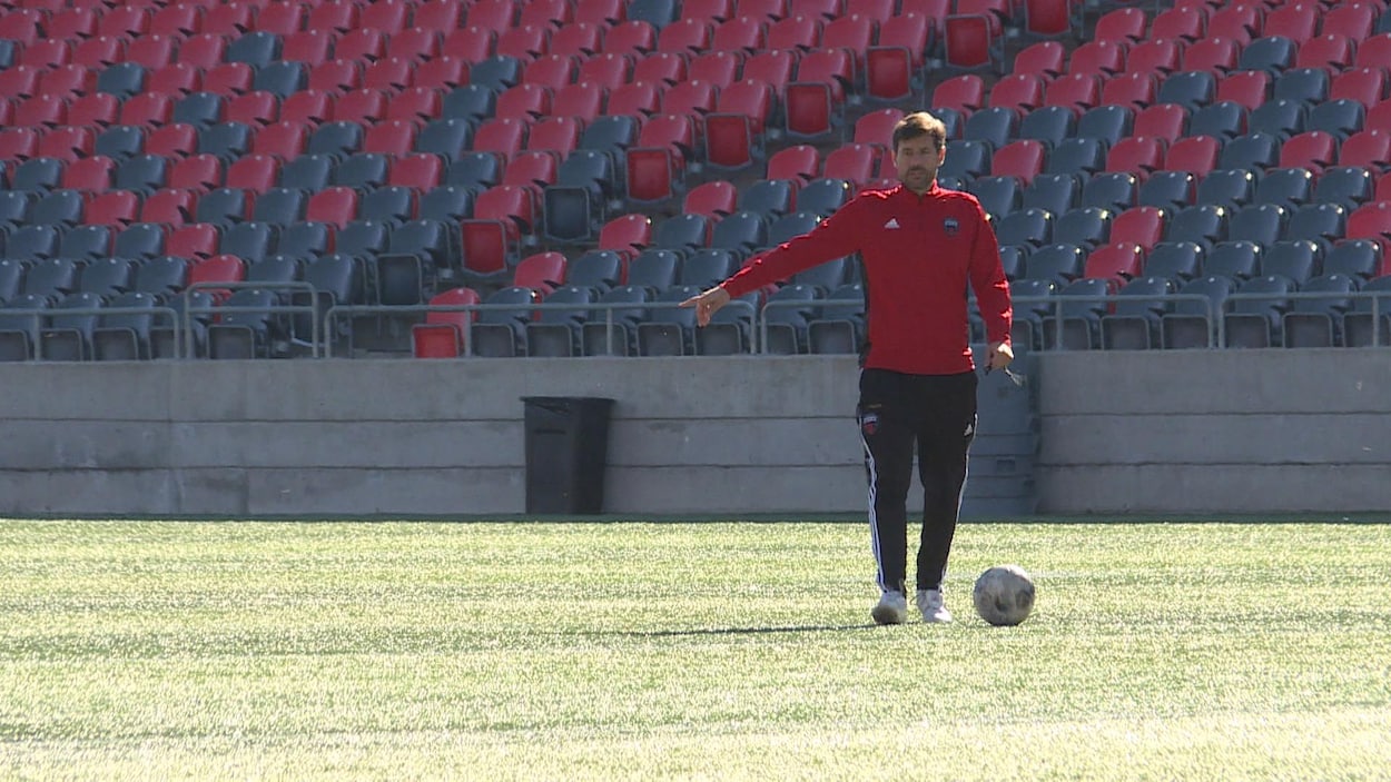 Un entraîneur de soccer dirige ses joueurs sur un terrain.