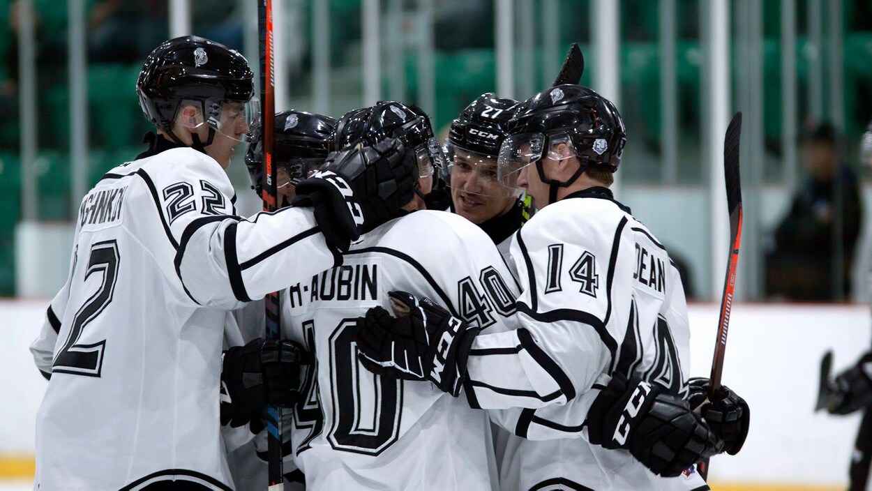Des joueurs de hockey s'enlacent après avoir marqué un but.