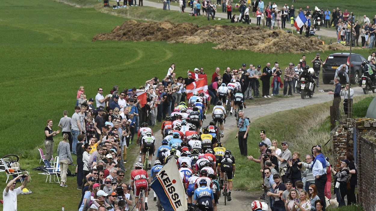 Des coureurs négocient les pavés de Roubaix dans des passages étroits, près de la foule Des coureurs négocient les pavés de Roubaix dans des passages étroits, près de la foule