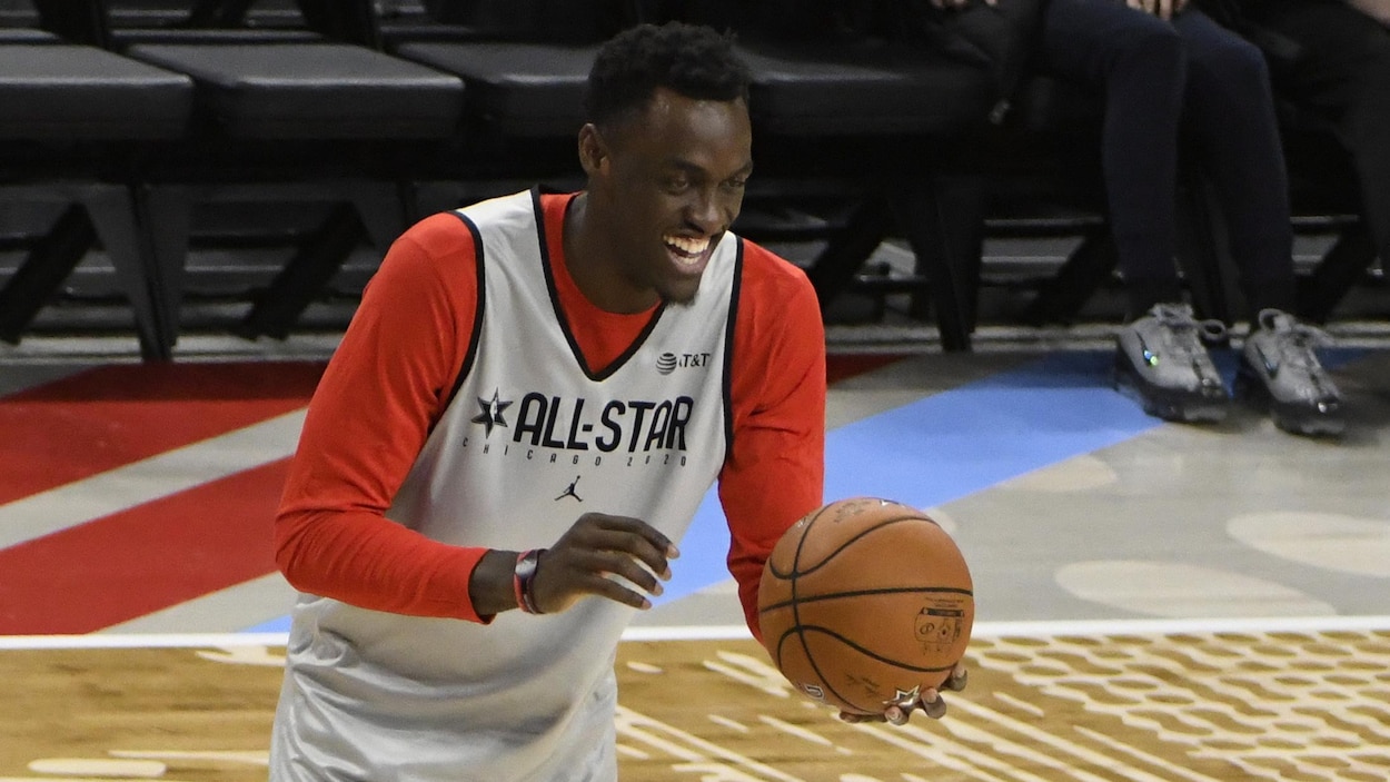Un homme tout sourire jongle avec un ballon de basketball.