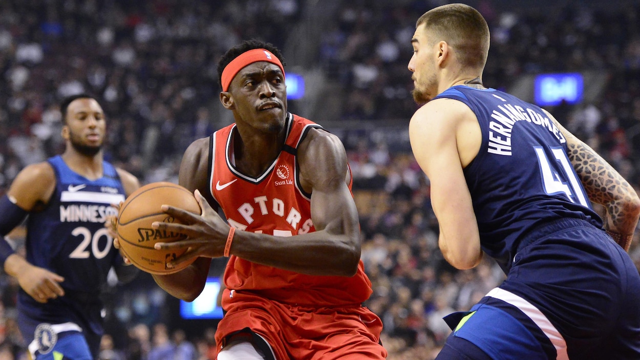 Il tient le ballon devant un joueur des Timberwolves.