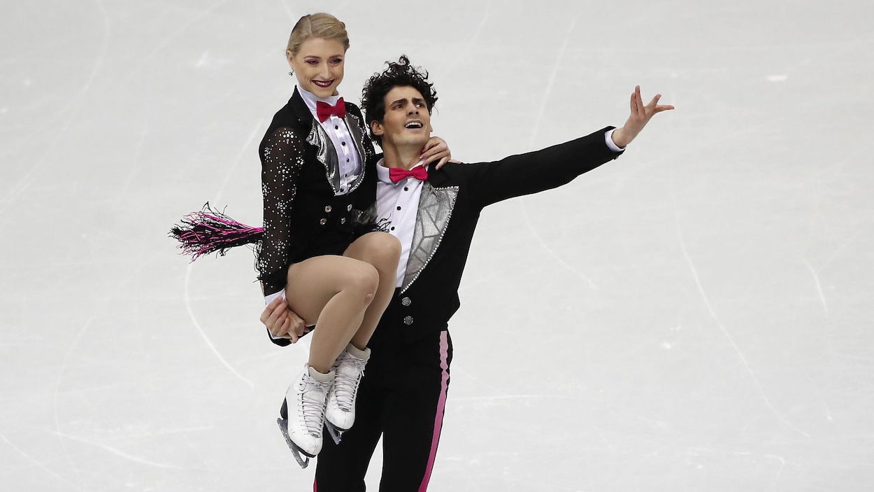 Le patineur porte sa partenaire sur son bras droit.