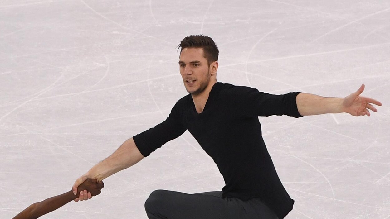 Il réalise une figure sur la patinoire.