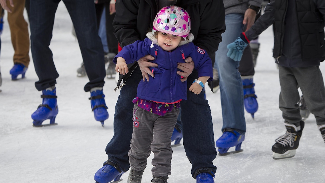 Une enfant reçoit un coup de main pour garder son équilibre en patins. Une enfant reçoit un coup de main pour garder son équilibre en patins.