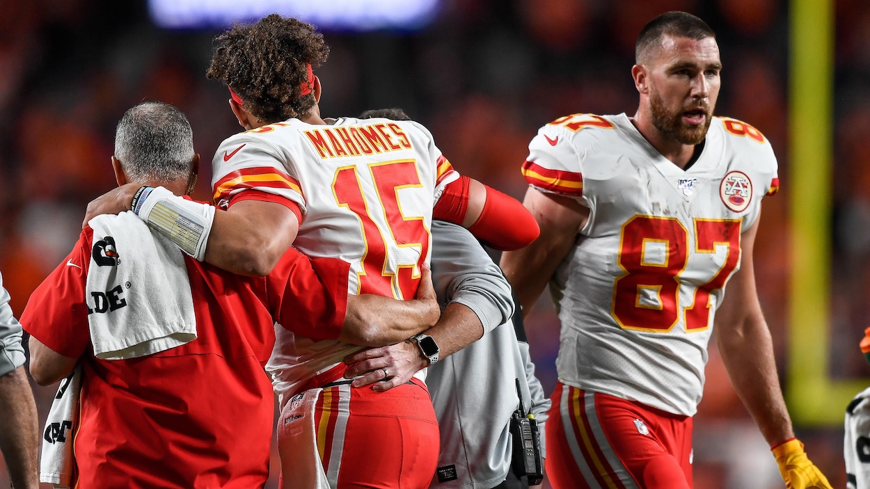 Mahomes est escorté hors du terrain par deux soigneurs.