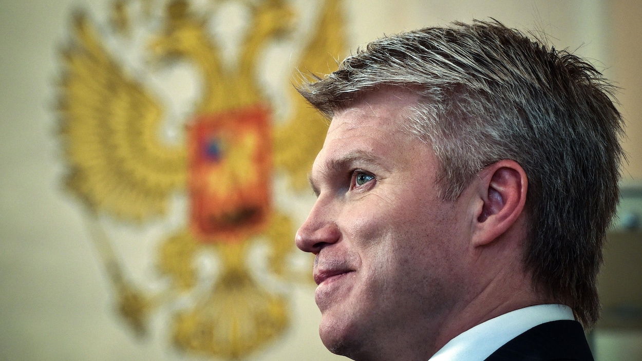 Un homme politique de profil devant l'emblème de la Russie