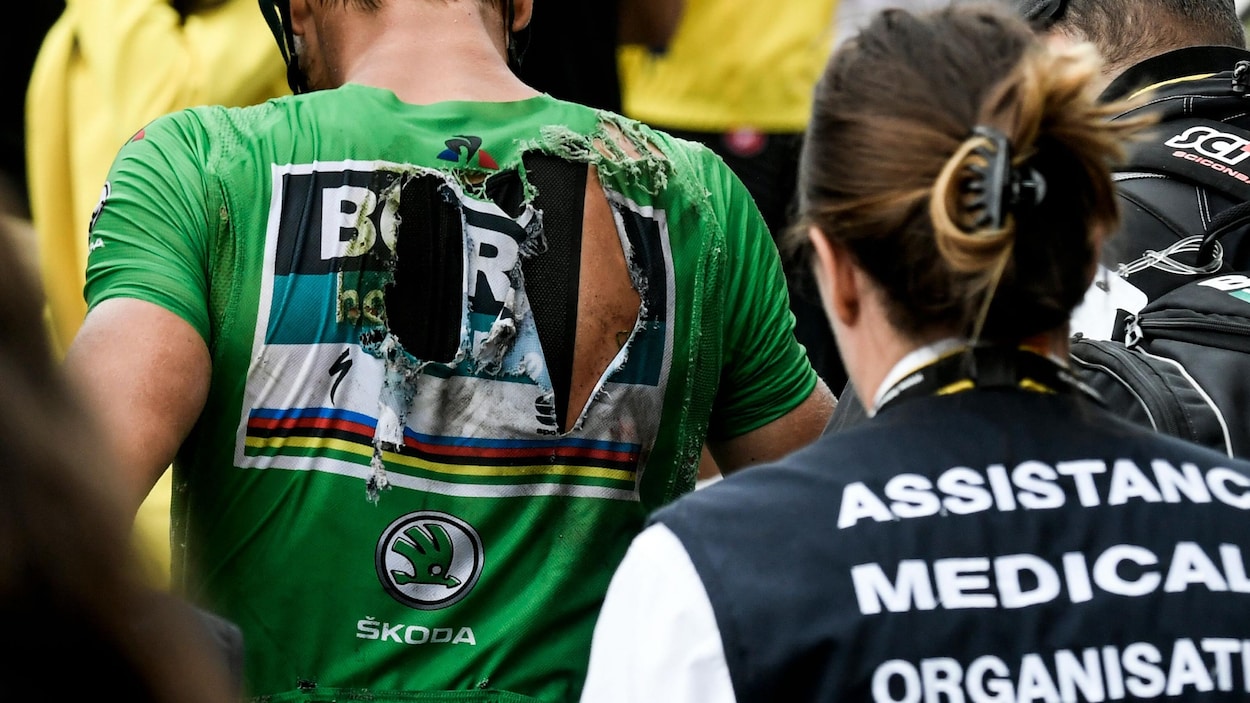 Un coureur, le maillot vert déchiré dans le dos à cause d'une chute.