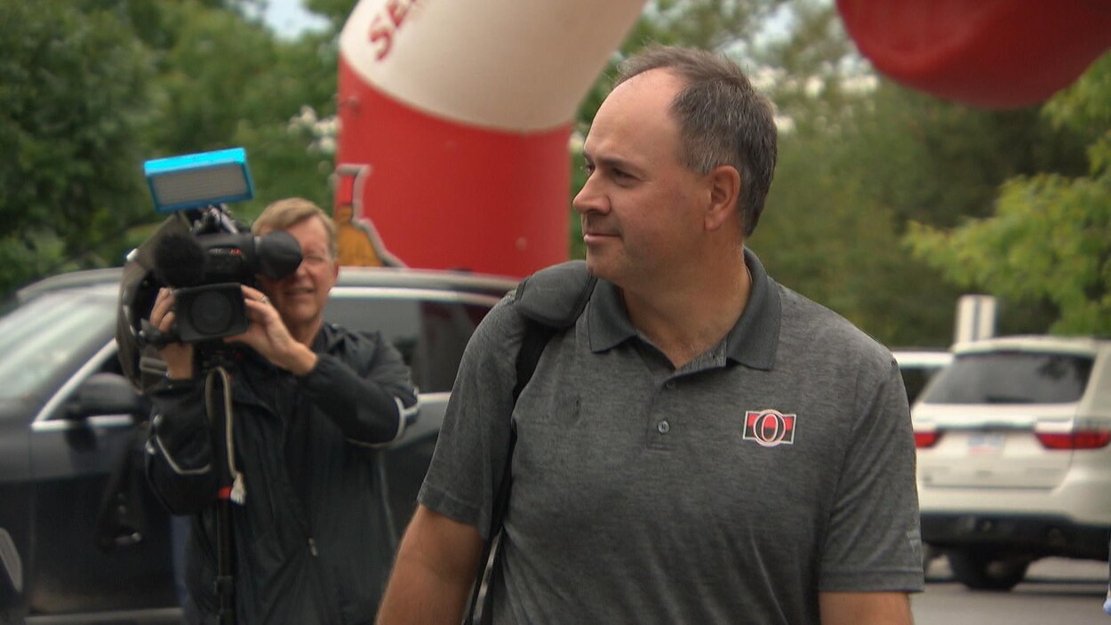 Pierre Dorion arrive sur un terrain de golf, suivi par les caméras des médias.