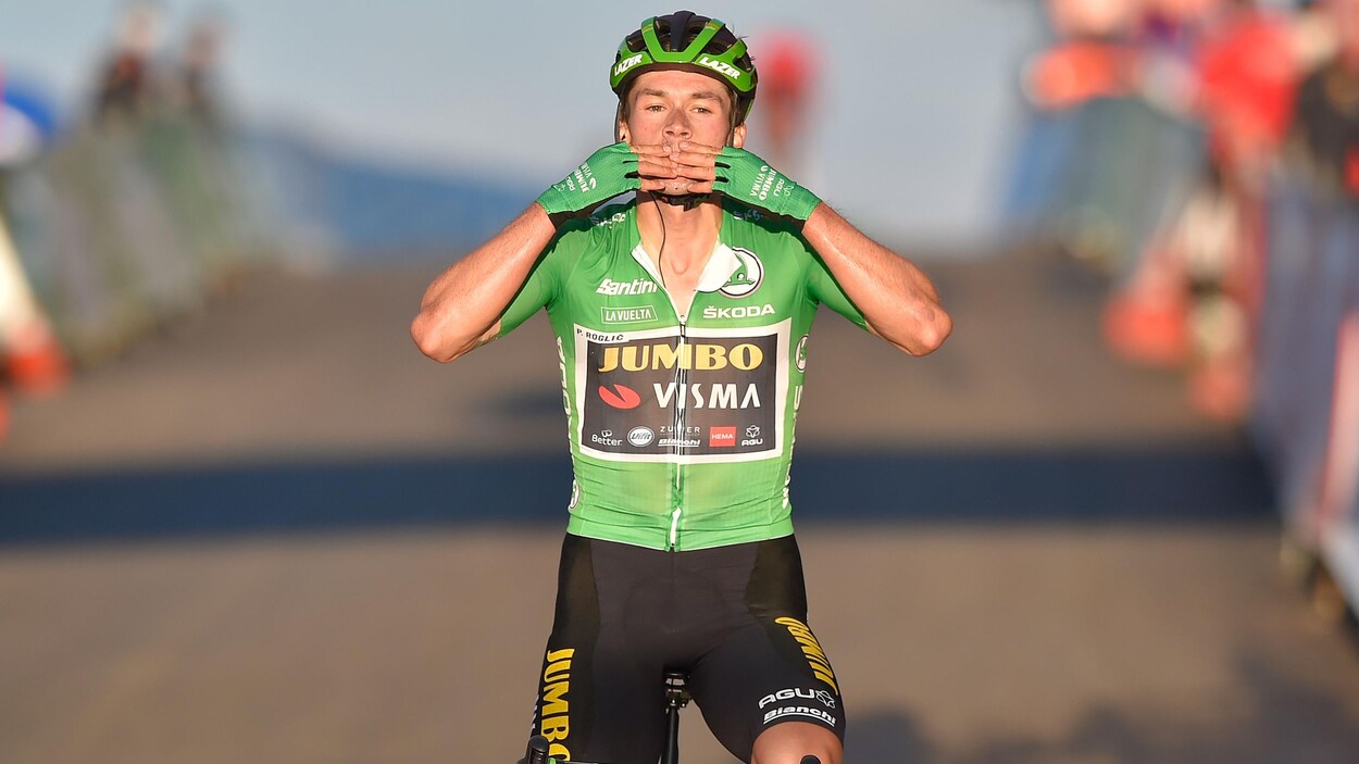 Il pose ses mains sur sa bouche en franchissant la ligne d'arrivée sur son vélo.