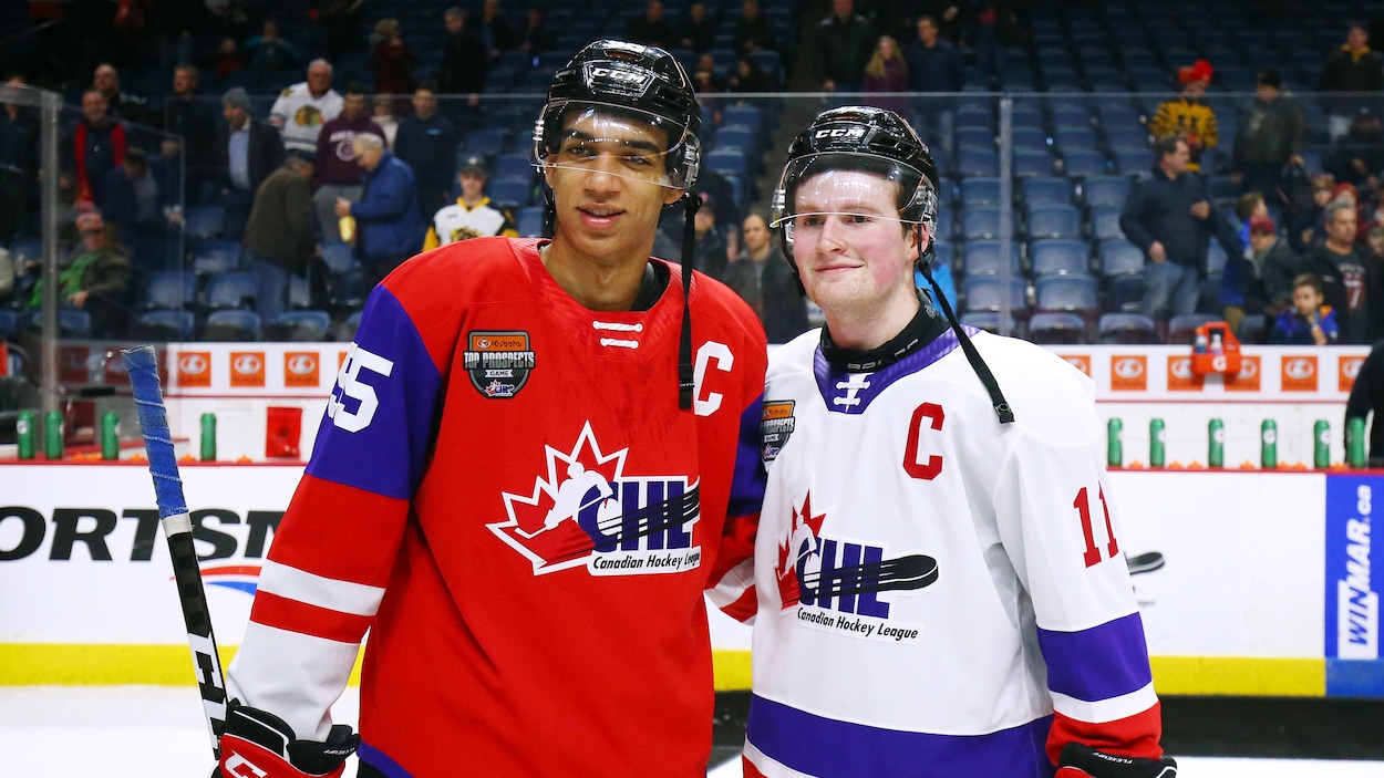 Deux joueurs de hockey se tiennent au milieu de la patinoire pour une photo.