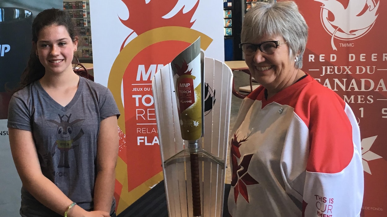 Mackenzie Van Damme et Lyn Radford, la présidente du conseil d'administration des Jeux d''hiver du Canada posent fièrement avec le flambeau.