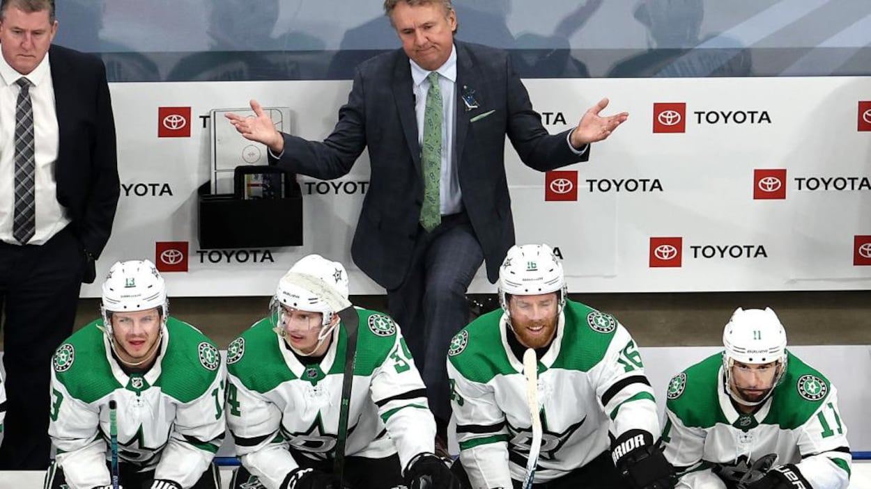 Il est debout derrière le banc des Stars.