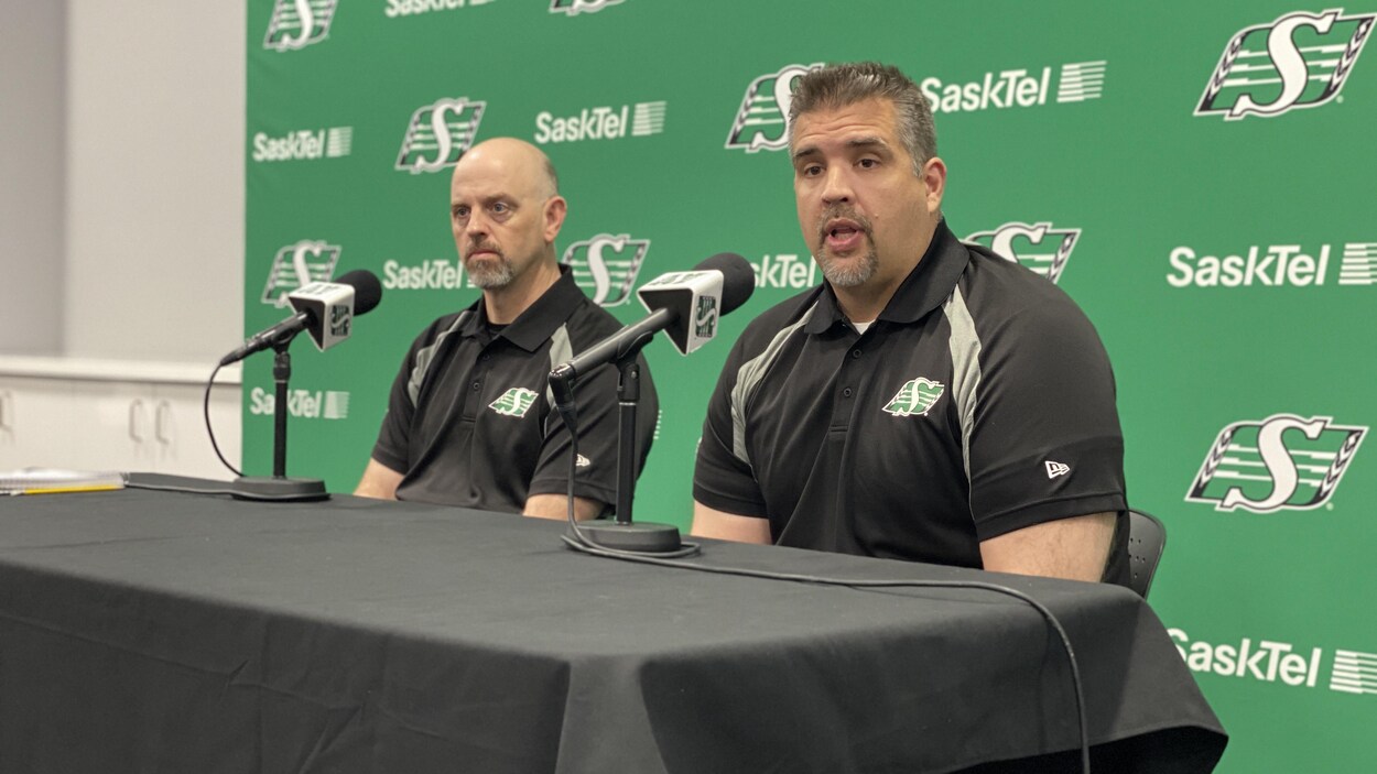 Deux hommes portant un polo des Roughriders en pleine conférence de presse.