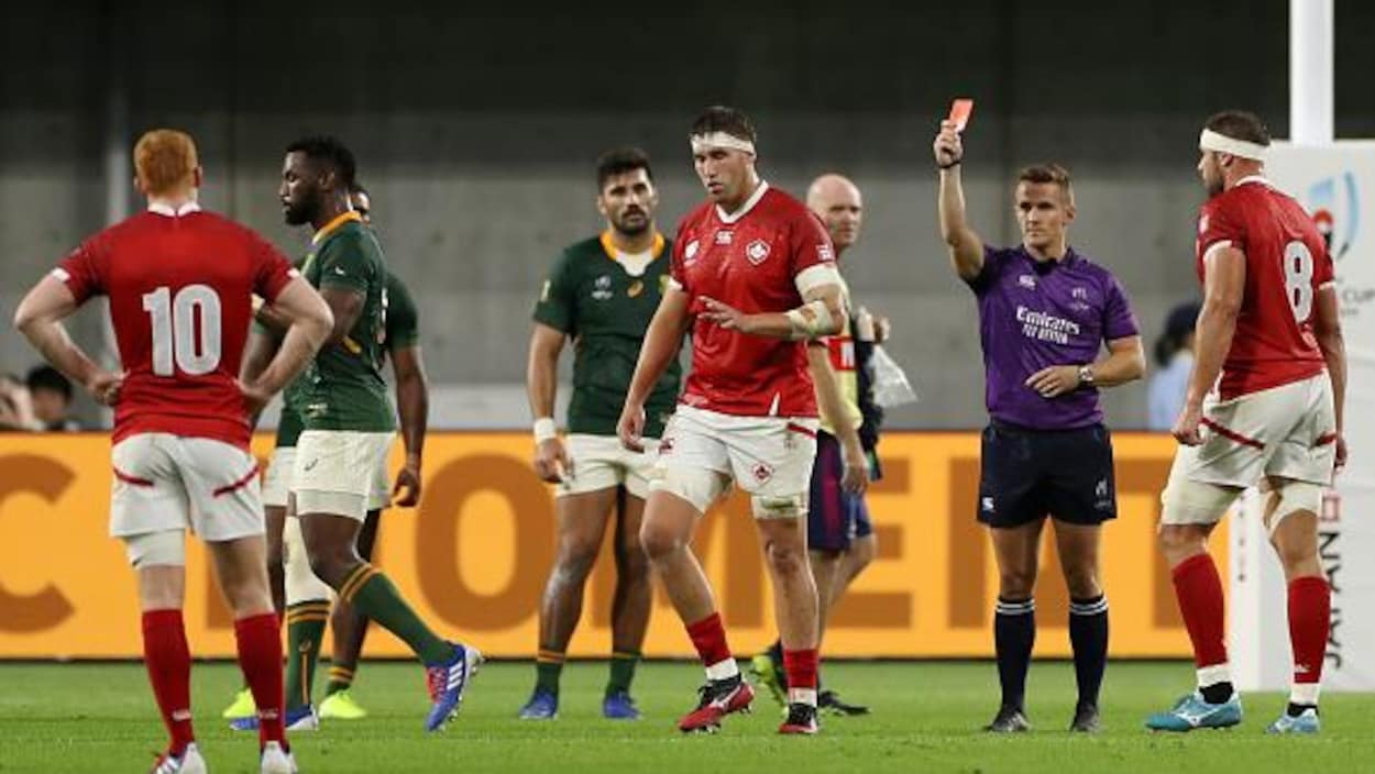 Un arbitre montre un carton rouge à un joueur qui lui tourne le dos.