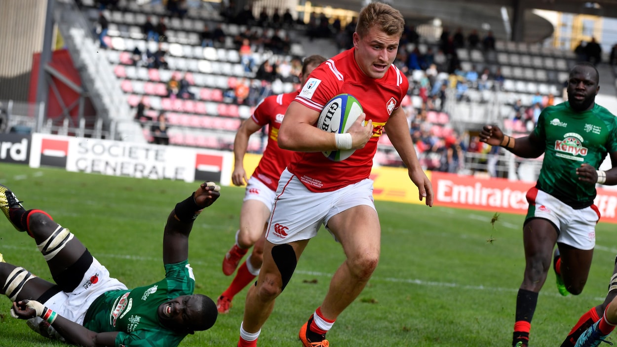Le Canadien Theo Sauder, ballon en main, double deux joueurs kényans au cours du match Canada-Kenya au tournoi de repêchage de rugby à XV.