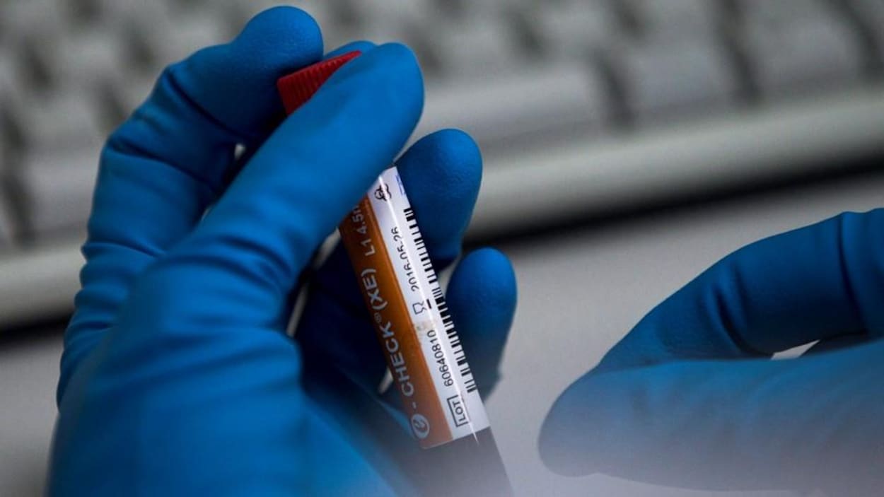 Une technicienne manipule l'éprouvette dans un laboratoire.