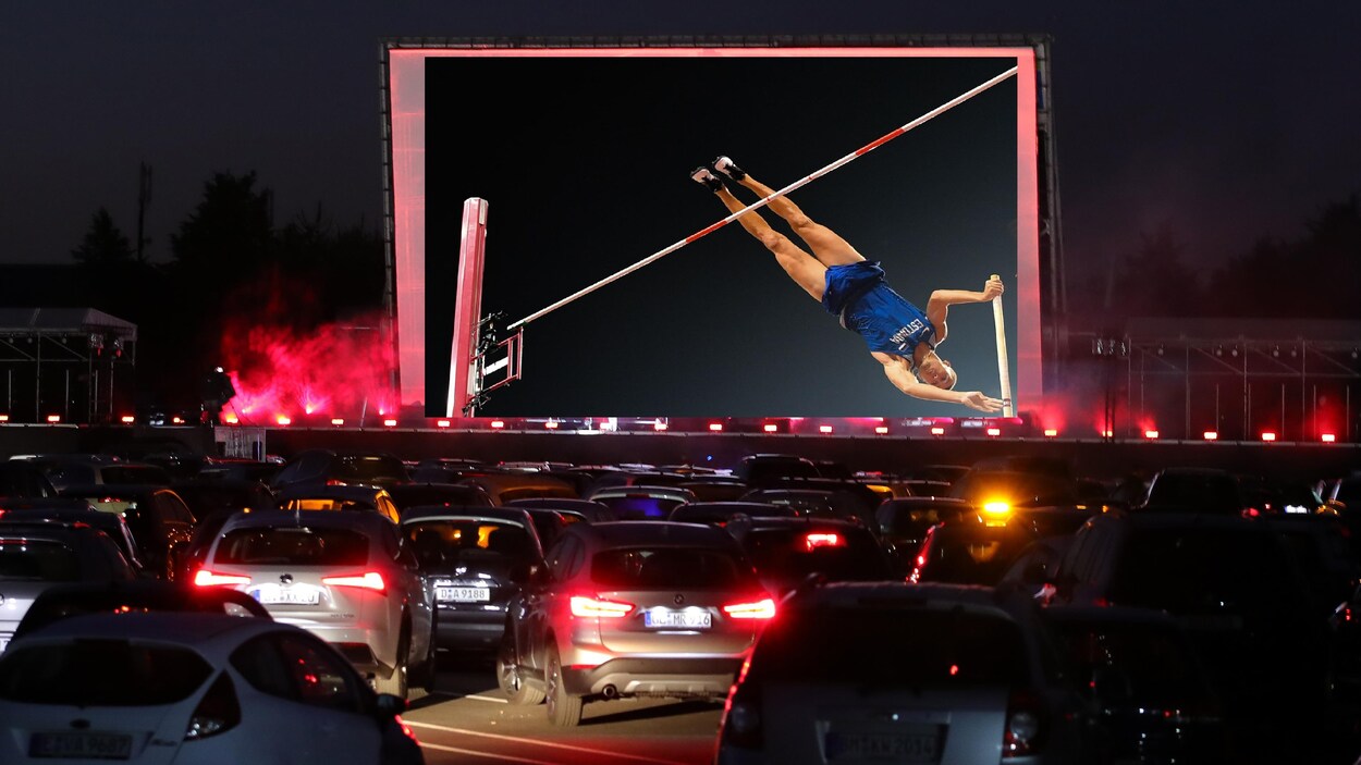 Des automobilistes regardent une rencontre de saut à la perche présentée dans un ciné-parc.